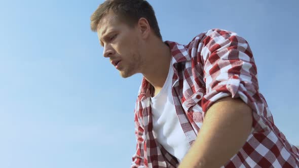 Scared Young Man Looking Down From Open Terrace, Fear of Heights, Acrophobia