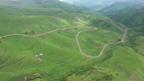 Top view of the mountain road through the green field