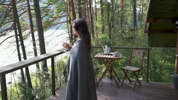 Beautiful Girl Wrapped in a Plaid on a Balcony in a Mountain House Enjoying a Glass of Wine alt