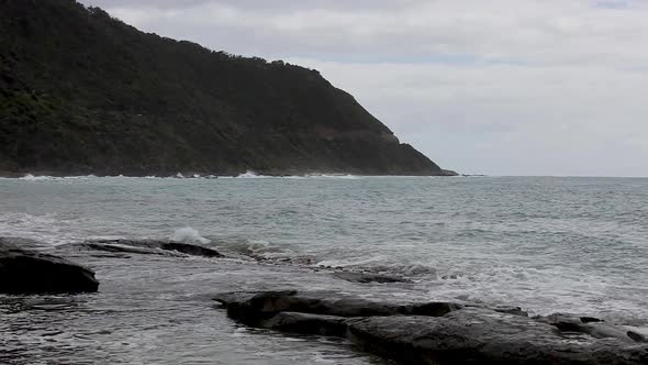 Great Ocean Road overcast sea landscape with waves rolling in and crashing against the rocks. alt