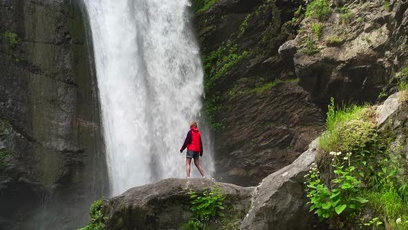 Hiking Woman in Red Jacket Walkng Near Big Waterfall