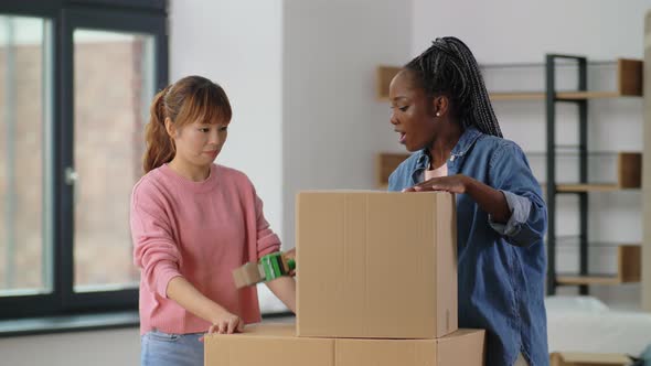 Women with Adhesive Tape Packing Boxes at Home alt