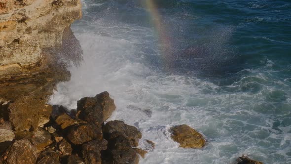 Sea waves breaking against cliff viewed from above. alt