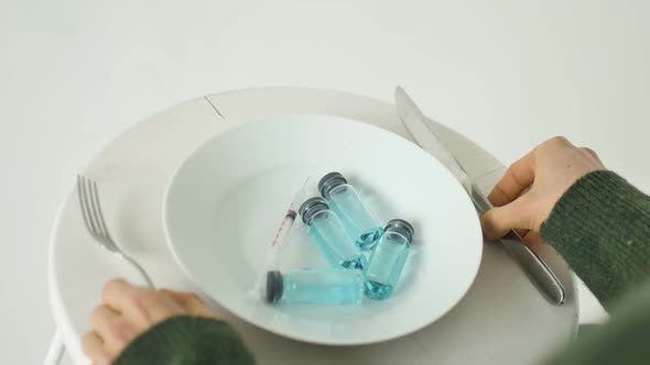 Woman is Going to Eat From White Plate with Glass Ampoules with Blue Liquid Inside Vaccination alt