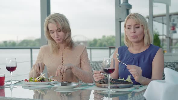 Front View of Adult Beautiful Women Eating Delicious Dishes in Outdoor Restaurant. Portrait of Rich alt