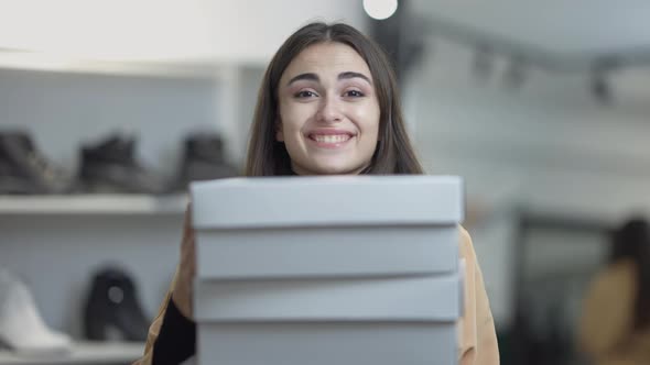Excited Gorgeous Slim Young Woman Smiling Looking at Camera As Female Hand Putting More Box on Stack alt