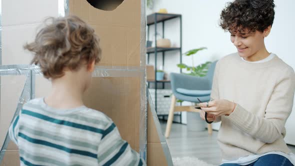 Portrait of Creative People Mother and Son Decorating Handmade Spaceship Playing at Home alt