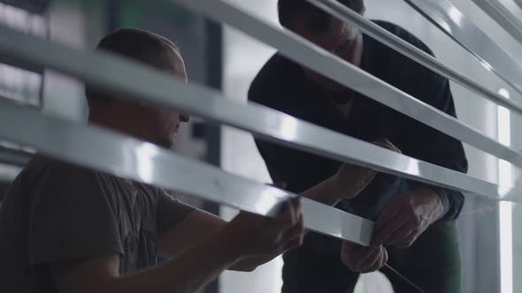 Closeup Two Male Painters Prepare Steel Metal Elements for Painting By Fixing Them on Suspensions alt