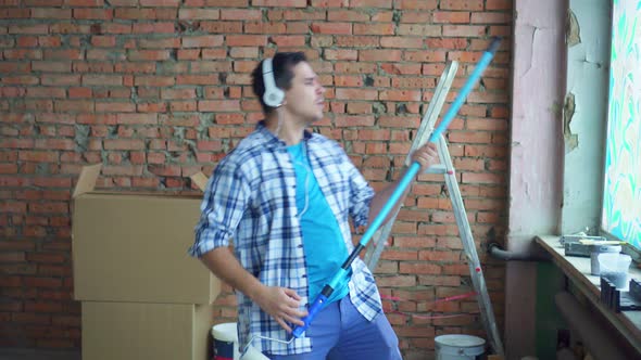 an Expressive Cheerful Man in a Shirt and Headphones During the Repair Plays an Imaginary Guitar alt