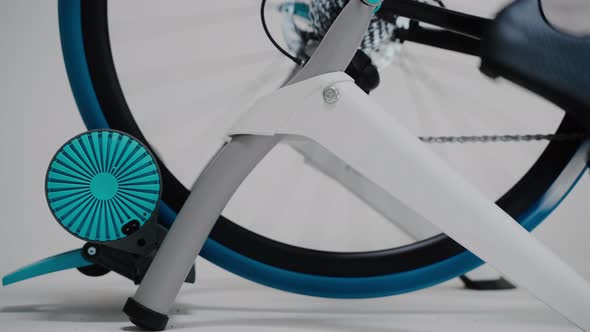 Rotating Rear Wheel of a Stationary Exercise Bike on a White Background alt