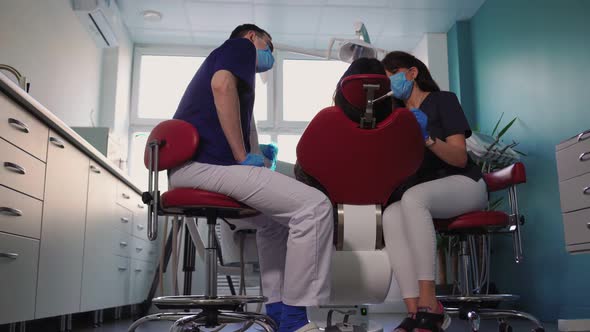 Doctors Dentists Woman and Man in Medical Masks Serve Patient in Dental Clinic alt