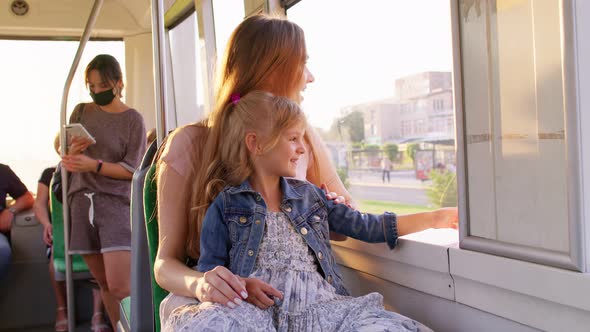 Family Rides in Public Transport Mother with Little Daughter Sit Together and Look Out Window Tram alt