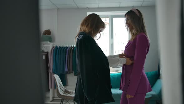 Woman Adjusting Garment on Friend in Shop alt