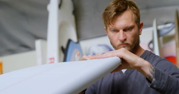Man examining a surfboard 4k alt