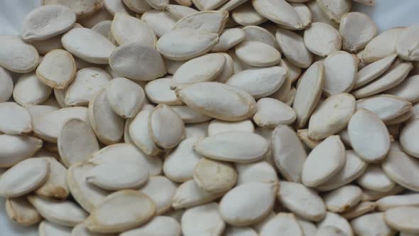 Close-up of a bunch of white pumpkin seeds rotating. Falling pumpkin seeds alt