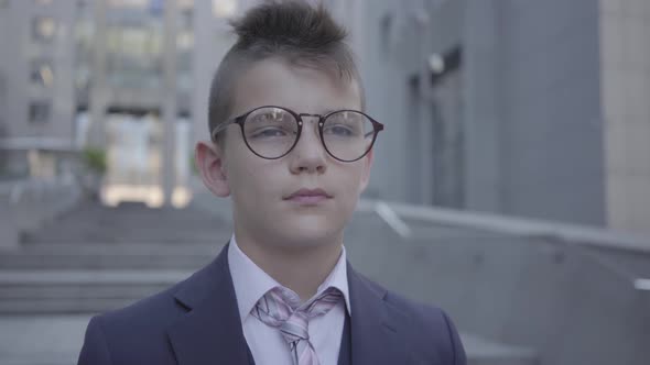 Portrait Handsome Well-dressed Boy in Spectacled Standing on the Street Looking in Camera alt