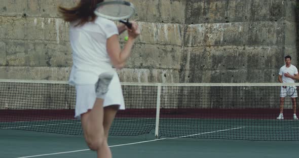 Woman and man playing tennis on a court alt
