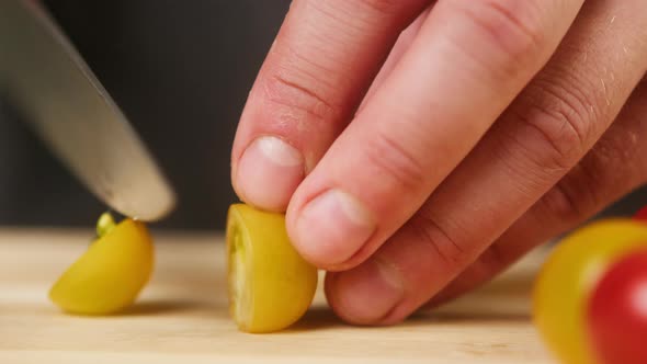 Professional Chef Cutting Cherry Tomato on Wooden Cutting Board Closeup alt