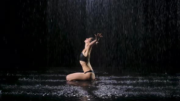 A Young Woman Sits on the Surface of the Water in the Studio and Meditates. The Female Enjoys the alt