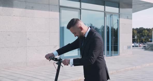Positive Businessman Enjoying Ride on Electric Scooter in Office Area alt