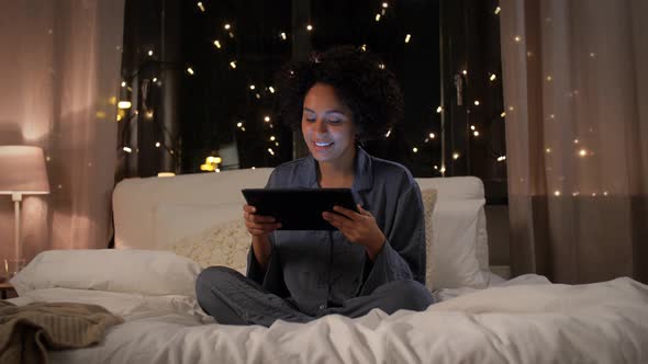 Woman with Tablet Pc in Bed at Home at Night