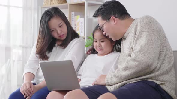 Happy young family with a kid sit on sofa in living room have fun using modern laptop together alt