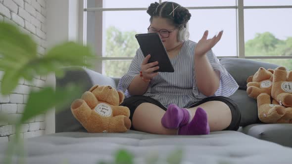 young Asian girl with Down's syndrome is playing a tablet alone in the room