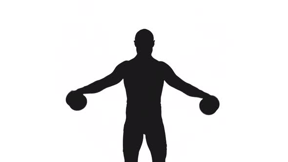 Silhouette Of Adult Male Athlete Lifting Dumbbells During Workout