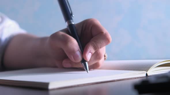 Close Up of Women Hand Writing on Notepad. alt