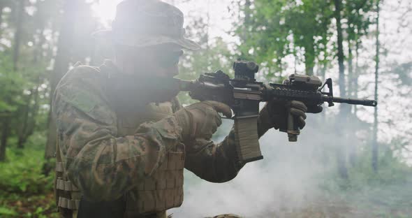 Modern Soldier with Rifle in Dens Forest with Smoke in Backgorund alt