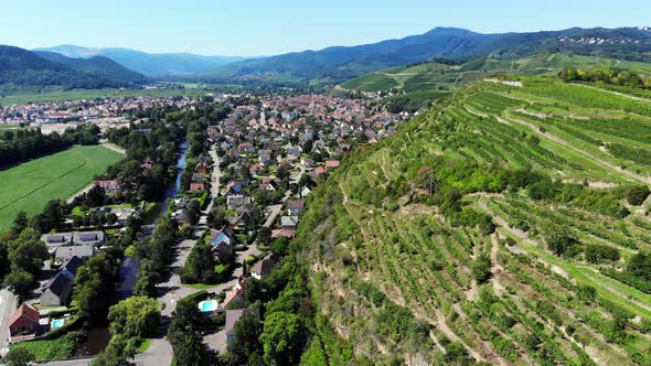 Scenic aerial shot of Turckheim town, hill with swathes of vineyards on right