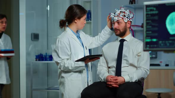 Man Sitting on Neurological Chair with Brainwave Scanning Headset alt