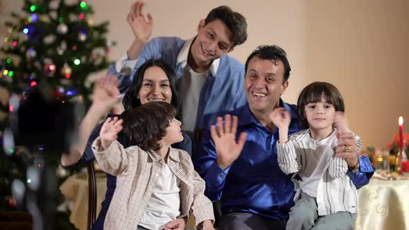 Positive Multiracial Family Waving Looking at Camera Smiling on Christmas Eve at Home alt