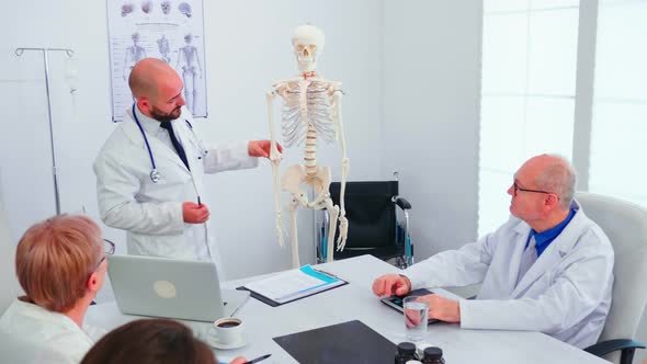 Expert Doctor in Radiology Pointing at Human Skeleton alt