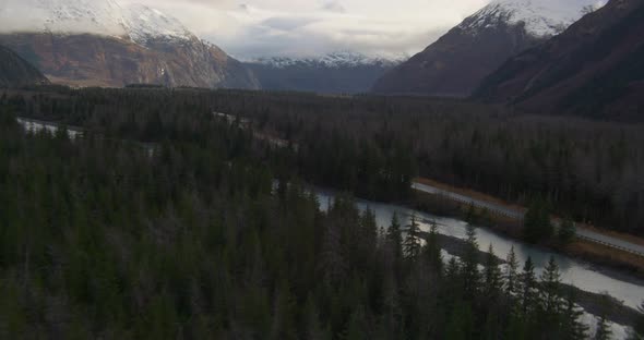 Aerial footage across snowy Alaskan mountaintops and clouds, drone helicopter footage alt