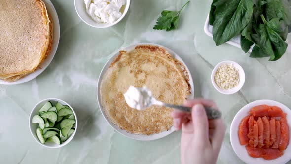 Woman Putting Ingredients on Pancake One By One for Maslenitsa alt