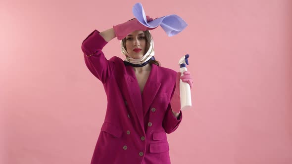 A Tired Young Woman Wearing Gloves Holds a Window Cleaner Spray