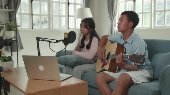Boy Playing Guitar And Girl Sing A Song While Streaming. The Children Is Broadcasting Live alt