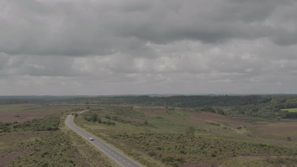 Aerial Drone Shot of English UK Countryside in The New Forest with Road and Cars in moody stormy wea alt