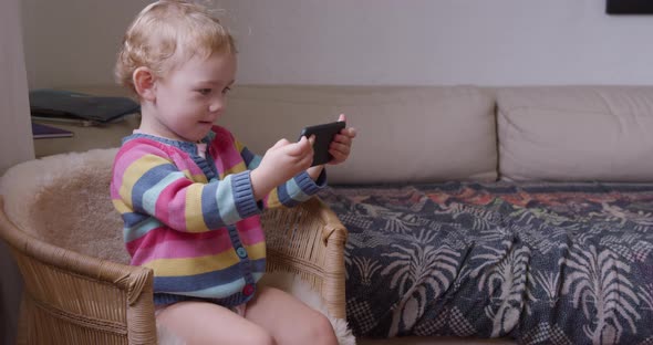 Baby playing on smartphone in living room at home alt
