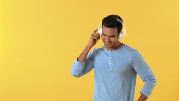 Happy young Indian man dancing while enjoying listening to music on headphones