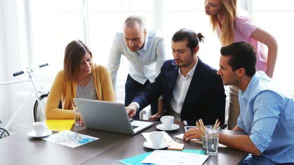 Business colleagues discussing over laptop alt