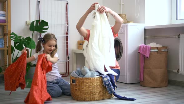 Mom and Daughter Doing Household Chores and Sitting on Floor in Home Laundry Spbd