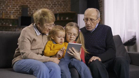 Family Using Tablet Pc on Sofa Together at Home alt