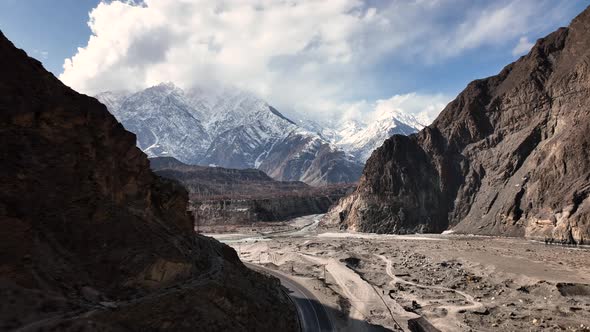 Drone Flying Through Shadow Of Valley To Reveal Snow Capped Mountains Of Hunza Valley. Dolly Forward alt