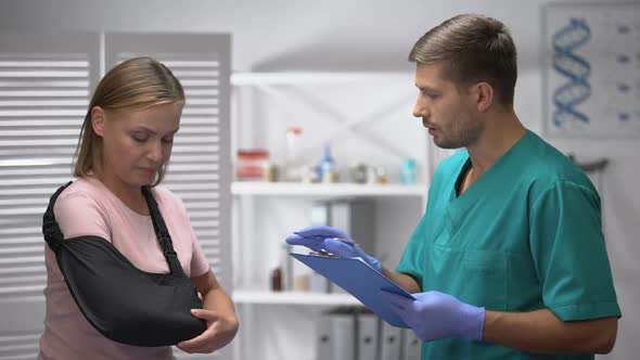 Experienced Surgeon Talking With Female Patient in Arm Sling Medical Examination