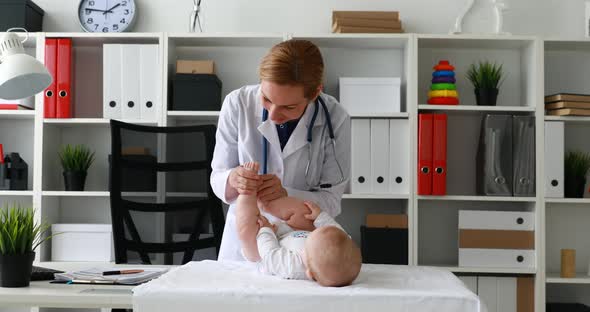 Pediatrician Playing with Child Lying on Table