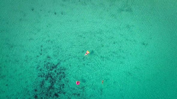 High aerial view of two young girls swimming and playing in sea with inflatables. alt