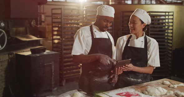 Animation of happy diverse female and male bakers using tablet alt