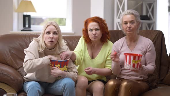 TV POV of Three Absorbed Caucasian Adult Women Watching Movie Eating Popcorn Sitting on Couch at alt